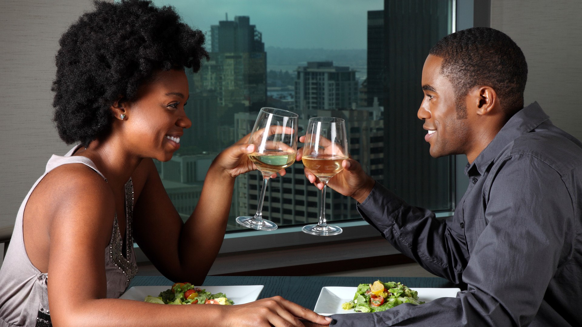 Expect something. An African Lady and guy in a conversation. People smiling and drinking. Getting ready to go out. Sit down Black man.